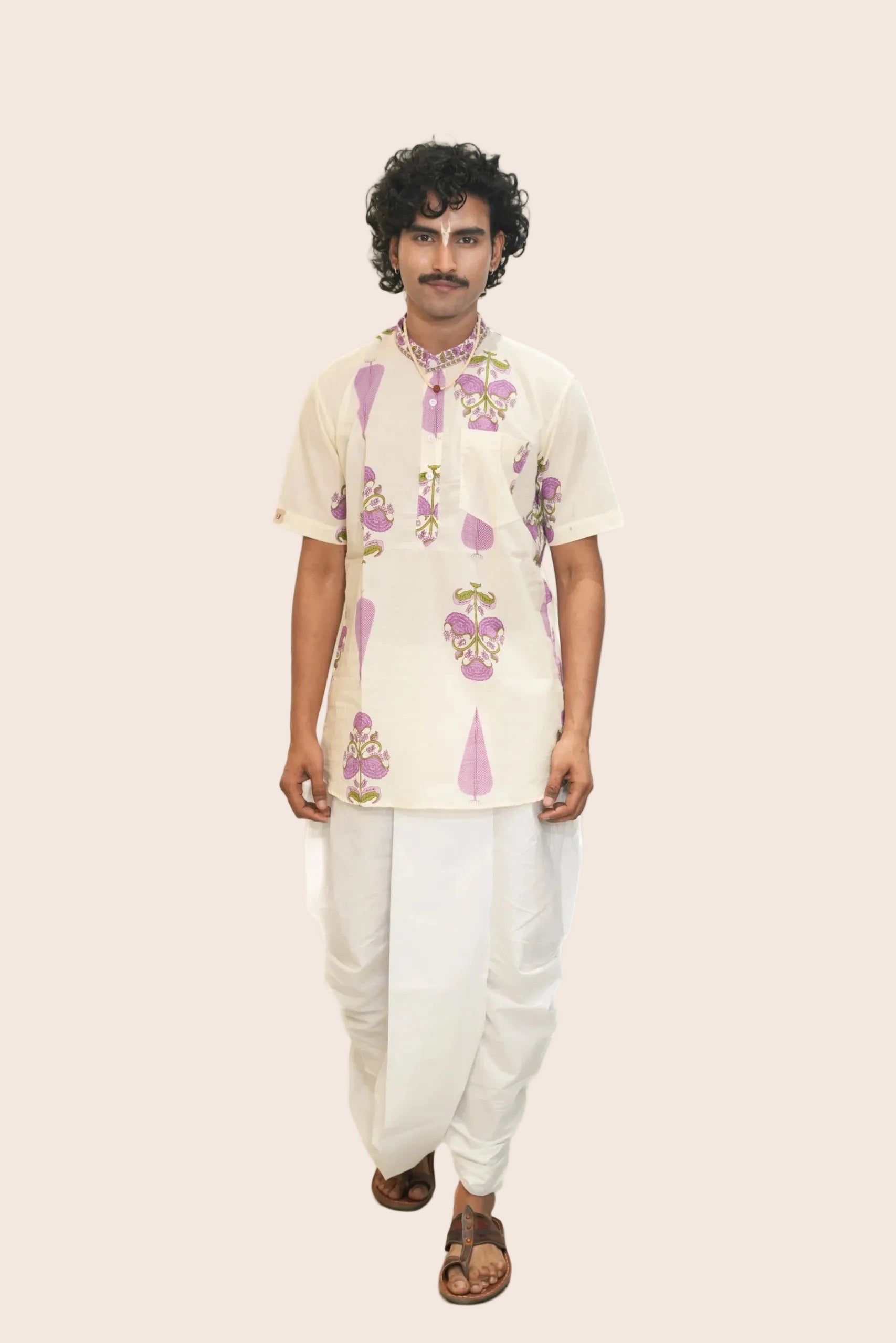 Man wearing a floral kurta with white pants on a white background