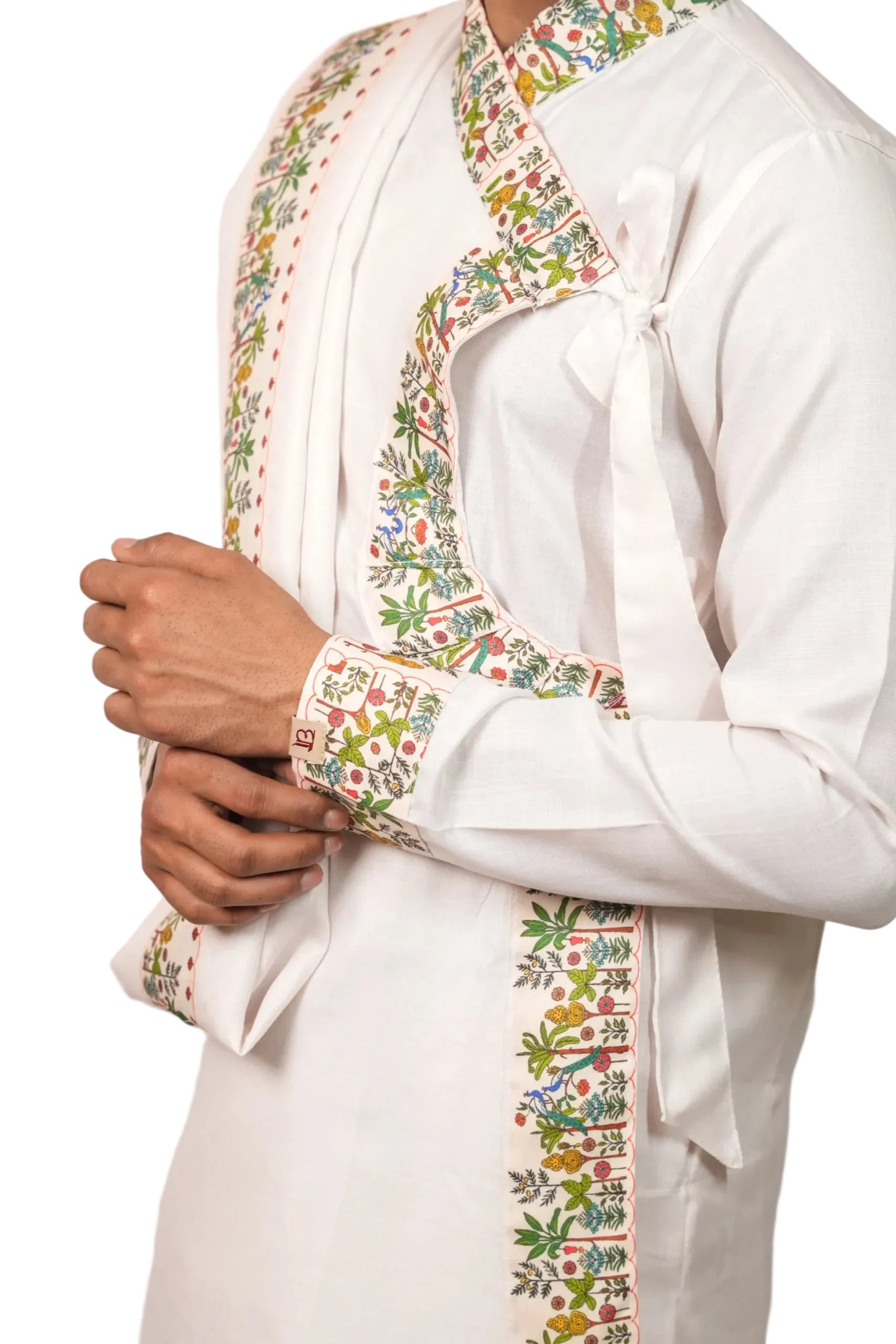 White traditional outfit with colorful floral embroidery on a plain background