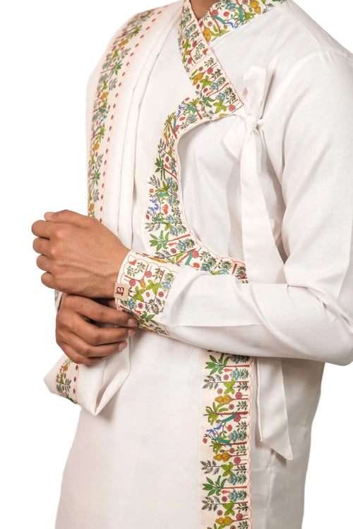 White traditional outfit with colorful floral embroidery on a plain background